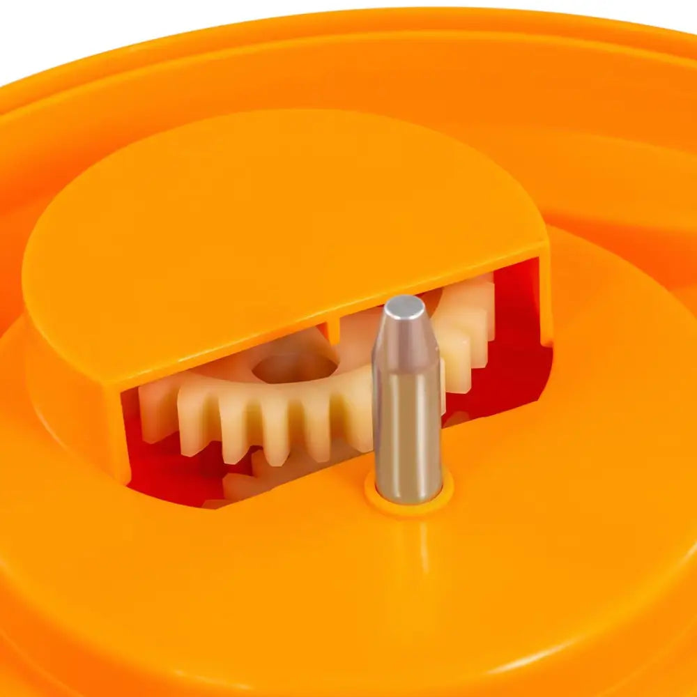Salatslynge manuell, nærbilde av oransje plastmekanisme med synlige lyse tannhjul og metallstift i sentrum.
