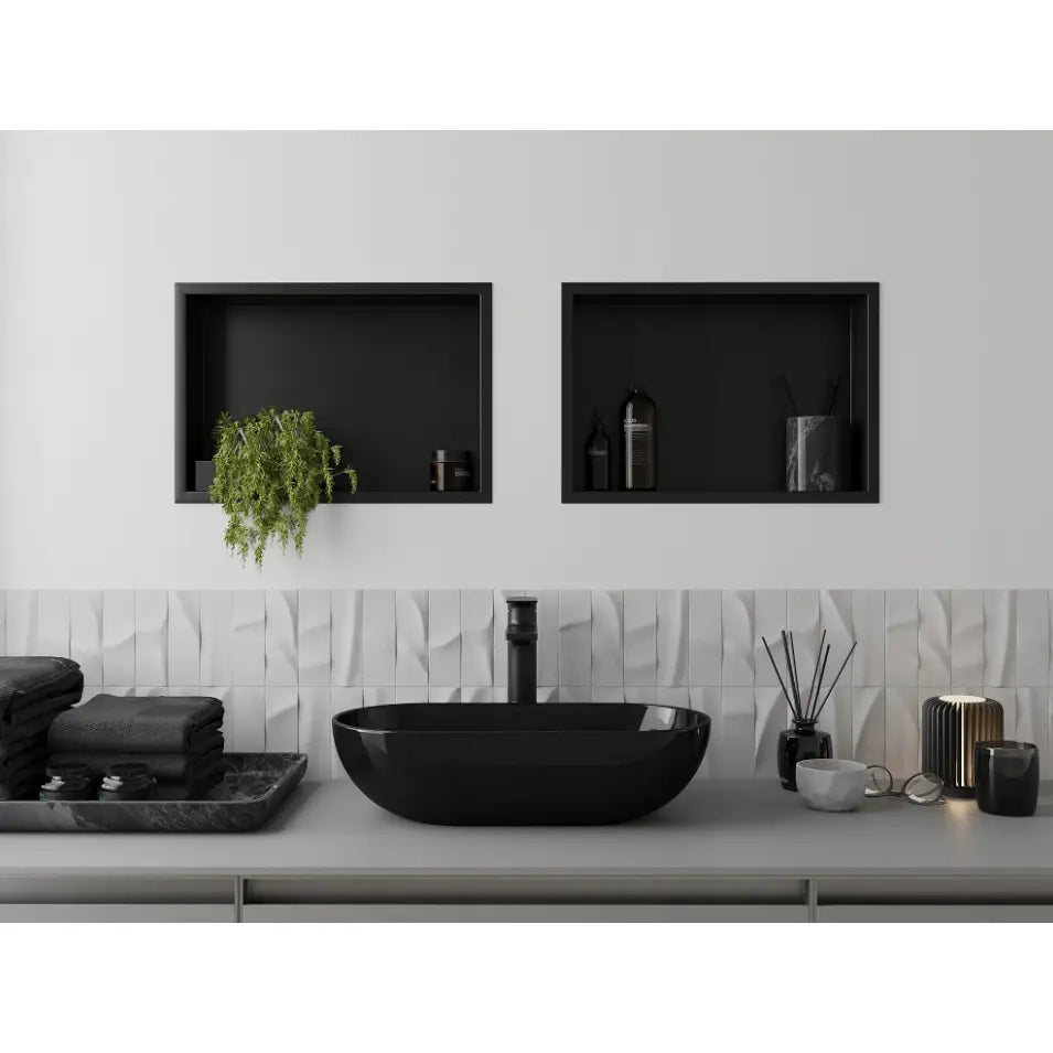 Sort høyglans servant på baderomsbenk, omgitt av svarte nisjehyller, duftlys og hvite, strukturerte fliser.
