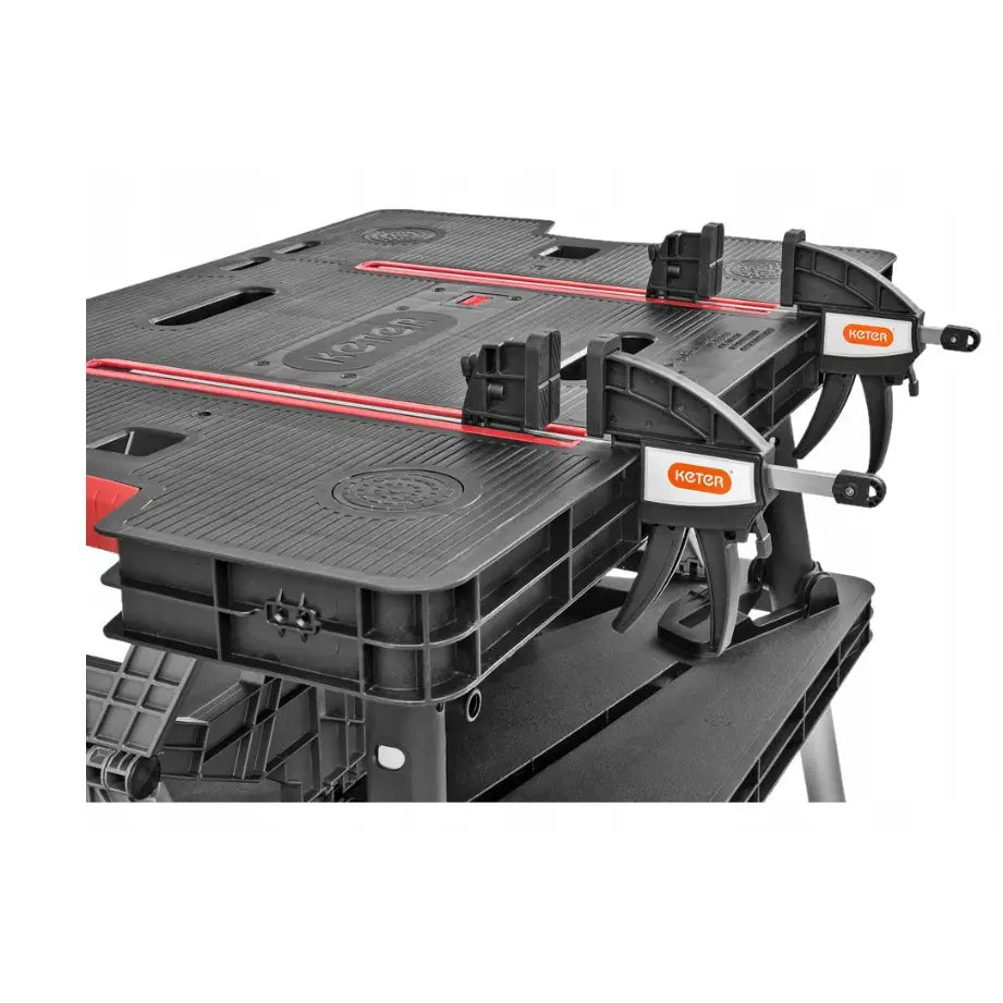 Sammenleggbar arbeidsbenk fra Keter, skråvisning med tvinger og røde detaljer på bordplaten.