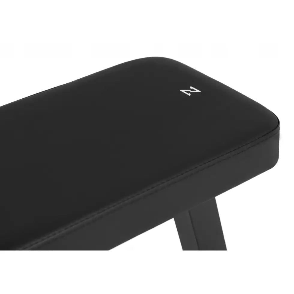 Sammenleggbar treningsbenk fra Zipro, nærbilde av polstret sort sete med synlige sømmer og hvit logo.