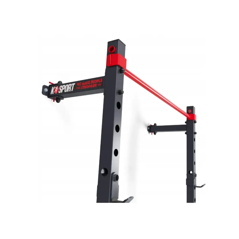 Sammenleggbar veggmontert rack i sort metall, røde detaljer og justerbare hull sett fra skrå vinkel.