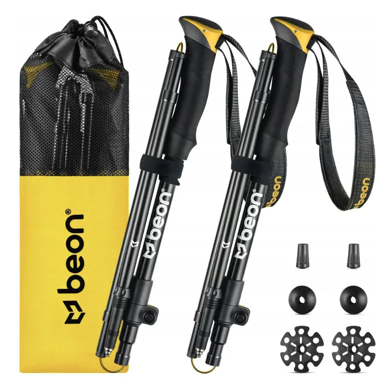 Sammenleggbare turstaver i sort og gul med ergonomiske håndtak, gummitupper og gul bærepose, sett forfra.