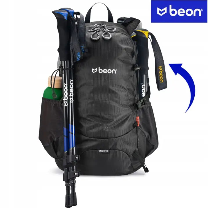 Sammenleggbare blå og svarte gåstaver festet på svart tursekk med refleks og synlig drikkeflaske.