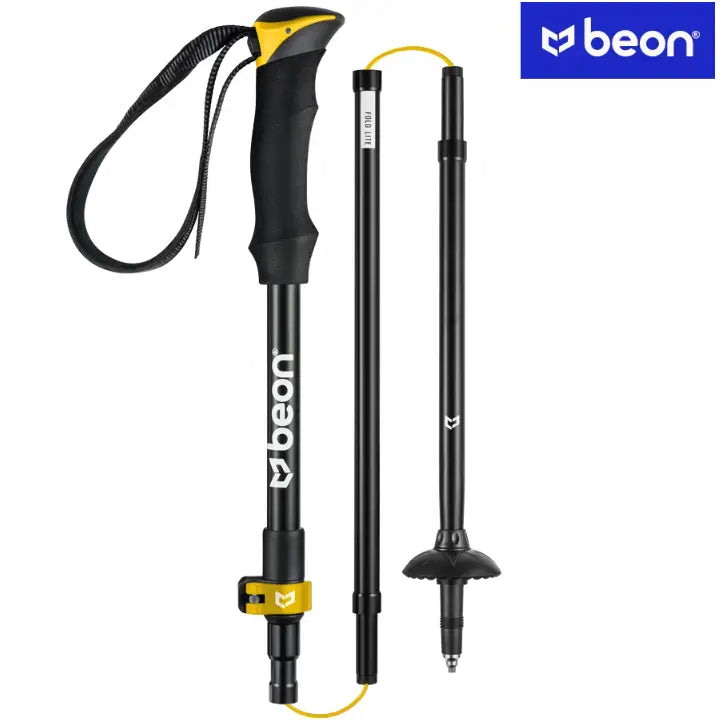 Sammenleggbar svart turstav i aluminium, delt i tre med gult grep, gul lås og tydelig hvit logo.