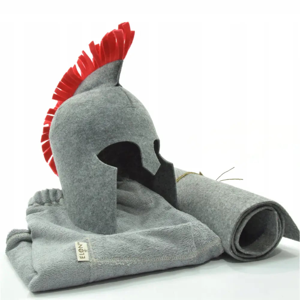 Saunasett for menn XL med grå filt-hjelm med rød kam, sammenbrettet håndkle og rullet filt på hvit bakgrunn.