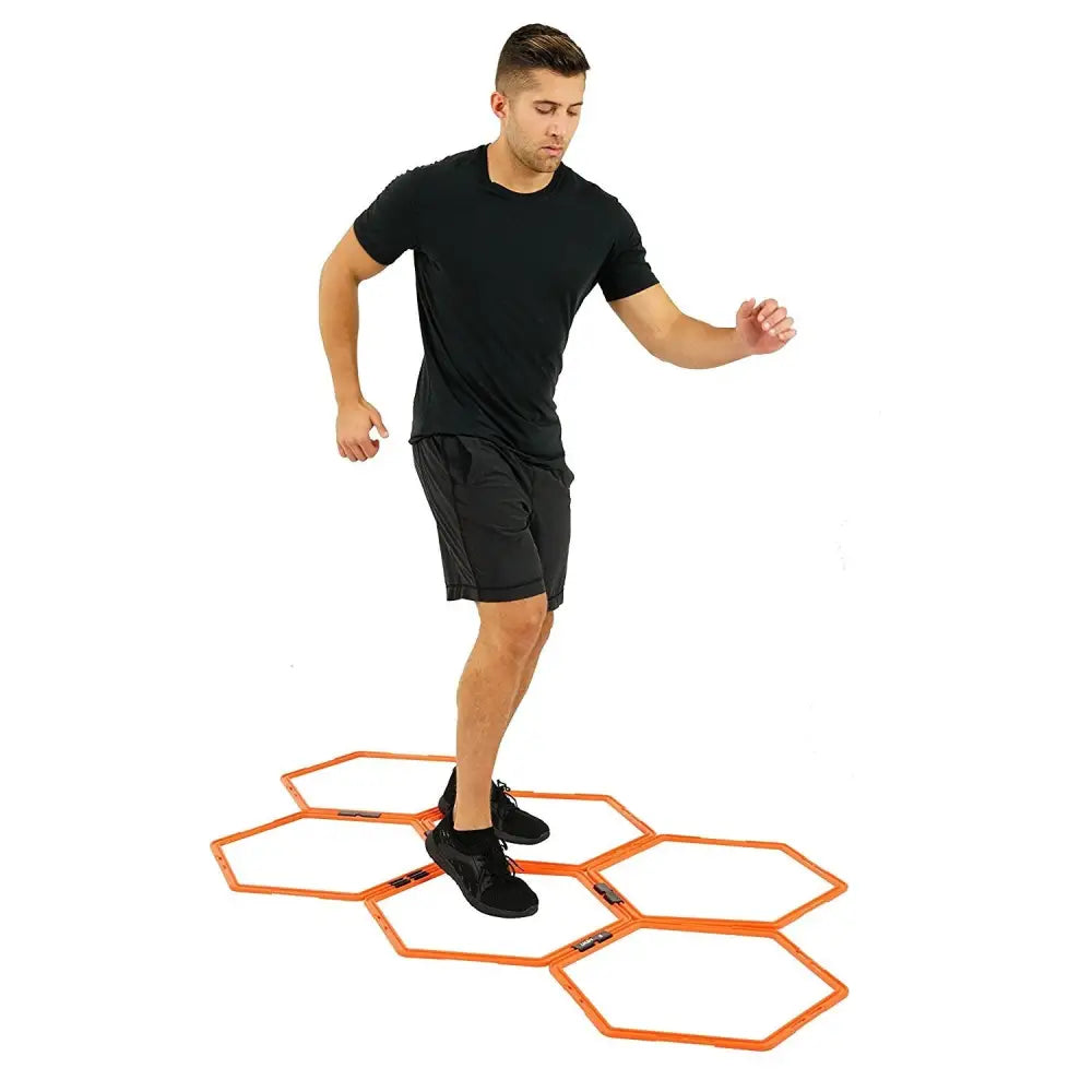Seks Hexa hoops sett i bruk, mann trener på oransje sekskantede agility-ringer mot hvit bakgrunn.