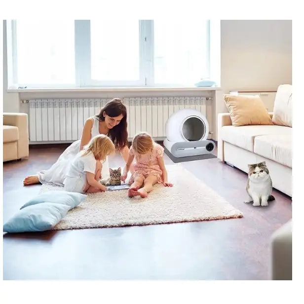Selvrensende Smart Wifi Kattetoalett (F054) plassert diskret i stuen bak en lekende familie og katt.