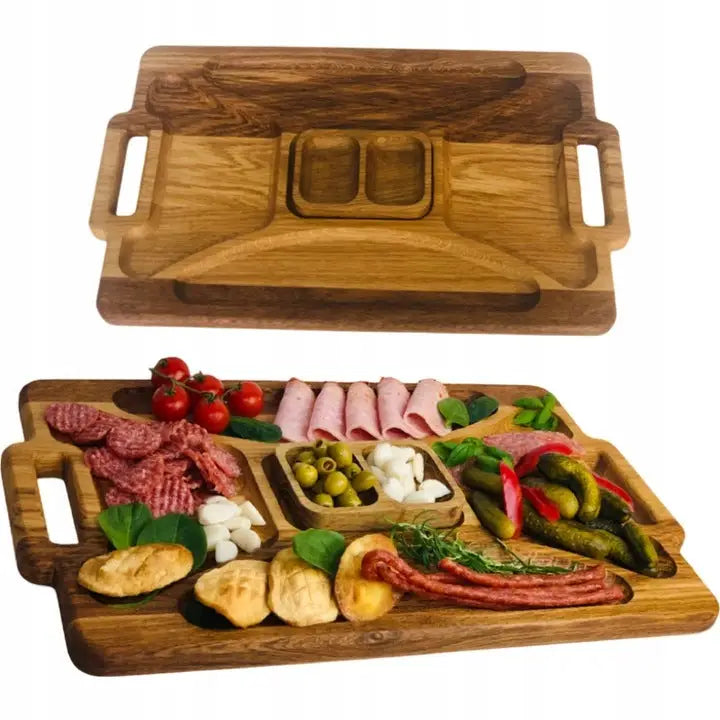 Serveringsbrett i lyst tre med håndtak og flere rom, vist med assortert pålegg og grønnsaker.