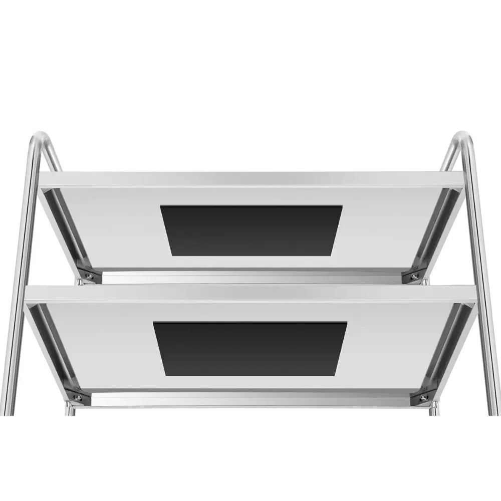 Serveringsvogn i rustfritt stål, nærbilde av to sølvfargede hyller med svarte rektangulære felt.