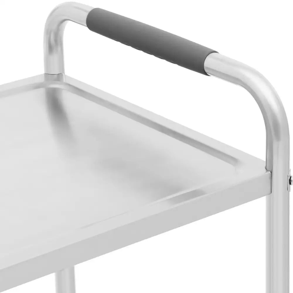 Serveringsvogn i rustfritt stål, nærbilde av sort håndtak og øvre hylle med glatt metallfinish.
