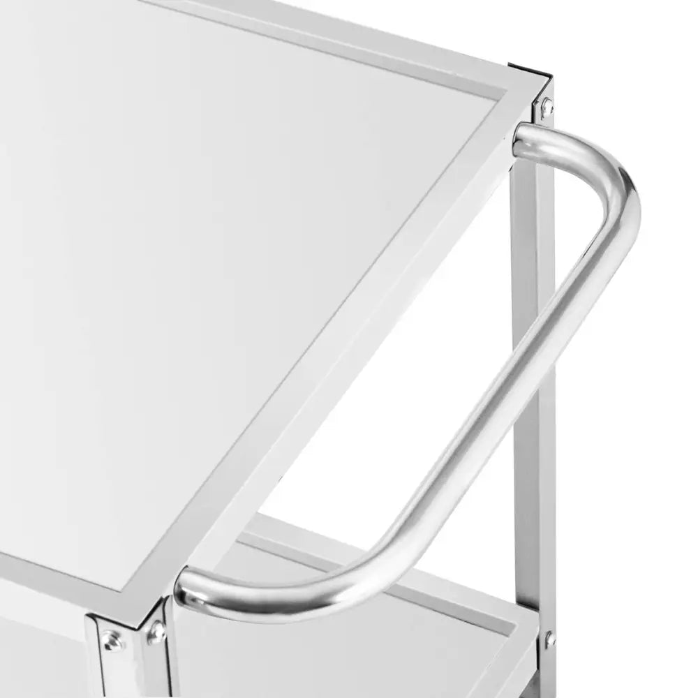 Serveringsvogn med to hyller, nærbilde av metallhåndtak og glasskant sett fra skrå vinkel.