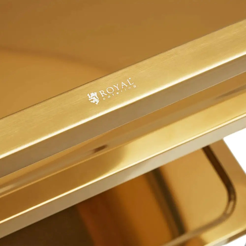 Serveringsvogn med 3 hyller i gull, nærbilde av blank metalloverflate og Royal Catering-logo på elegant kant.