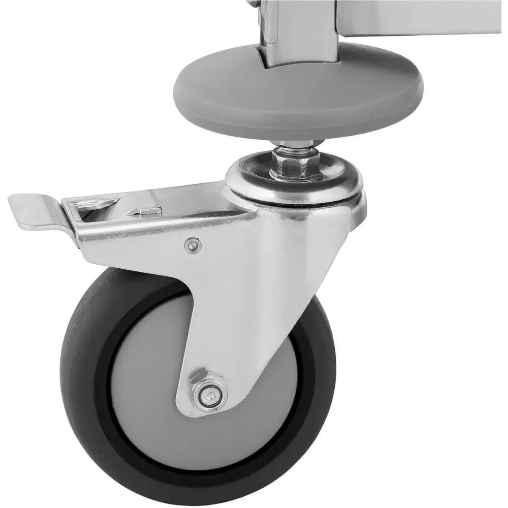 Serveringsvogn, nærbilde av hardplast hjul med sort kant og tydelig bremsespak i sølvfarget feste.