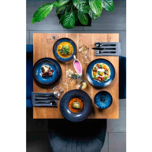 Servise Cosmos, fire mørkeblå tallerkener med mat, bolle og sausmugge, sett ovenfra på lys bordflate.