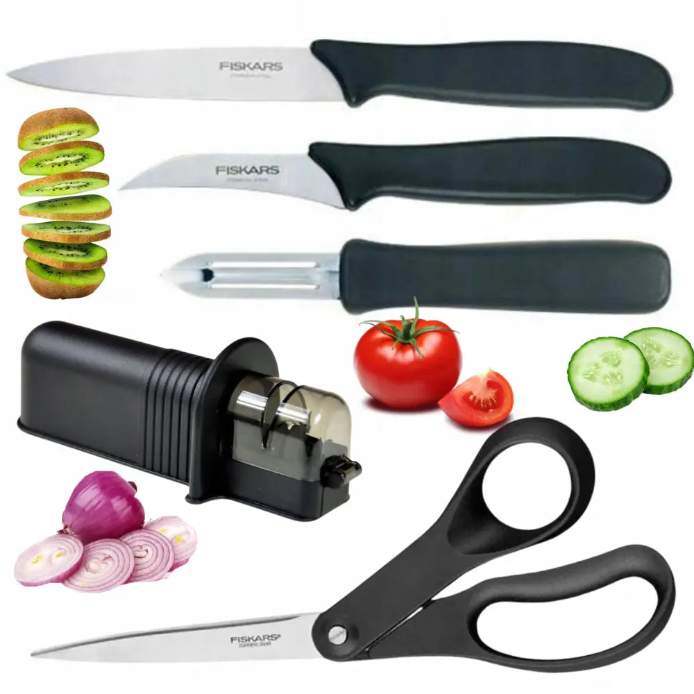 Sett med tre Fiskars kjøkkenkniver, grønnsaksskreller, knivsliper og saks med svarte håndtak, vist med frukt og grønnsaker.