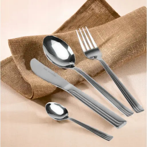 Sett med bestikk i rustfritt stål, fire deler med blank finish, fotografert ovenfra mot brun serviett.