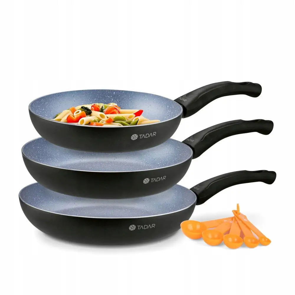 Sett med nonstick stekepanner i marmorlook, tre størrelser stablet, lyseblå belegg og oransje måleskjeer.