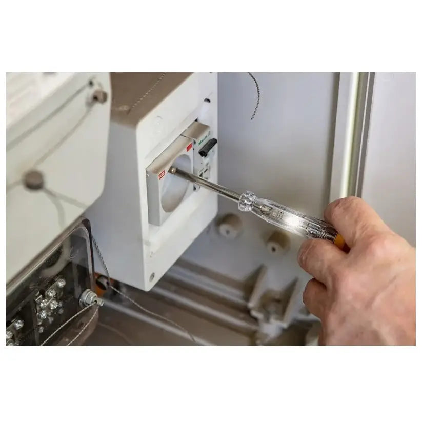 Sett med tang og skrutrekkere, gjennomsiktig skrutrekker i bruk på hvit kontakt, nærbilde fra siden.