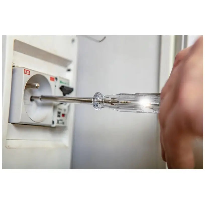 Gjennomsiktig skrutrekker med lys brukes i stikkontakt, nærbilde av hånd som holder verktøyet fra siden.