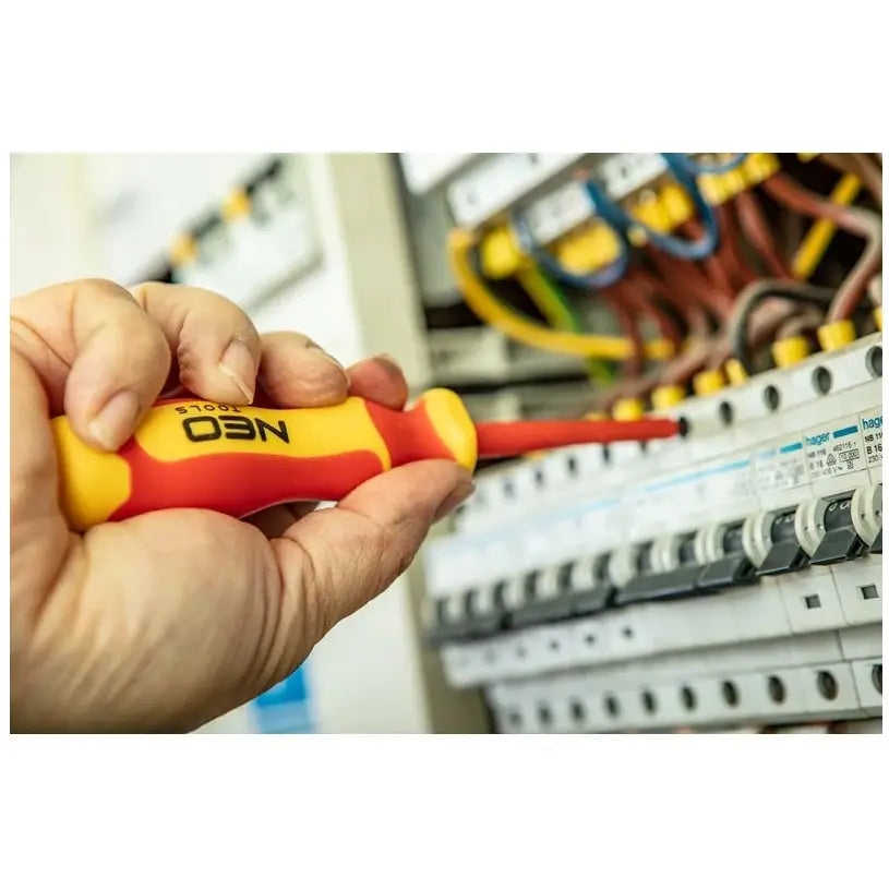 Skrutrekker med isolert skaft brukes på sikringsskap, nærbilde av verktøyet i bruk for elektrikerarbeid.