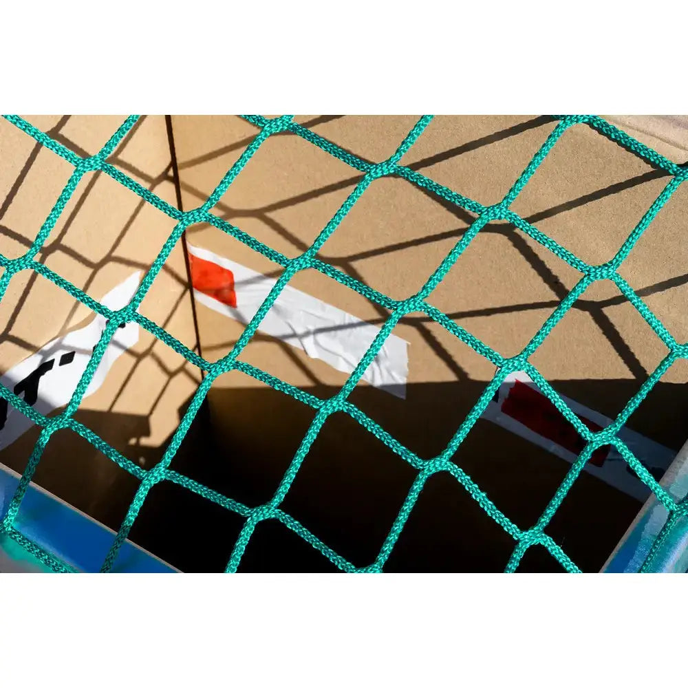 Sikkerhetsnett for tilhengere, grønt flettet nett strukket over store pappesker med synlige masker og skygger.