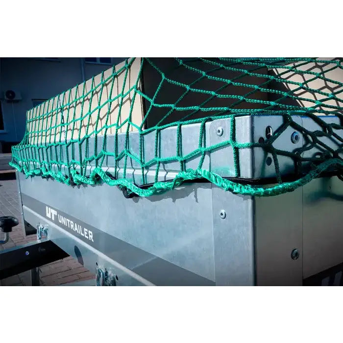 Sikkerhetsnett for tilhengere, grønt tettmasket nett stramt over last med forsterkede kanter, sett fra hjørne.