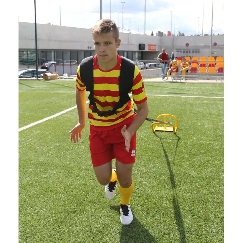 Sikkert treningsvekt 9 kg, ung mann drar gul treningsslede med sort sele på kunstgressbane under trening.