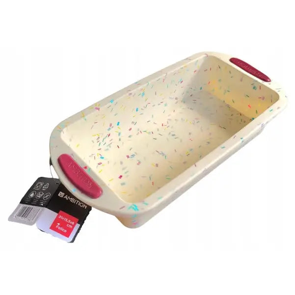 Silikonmatte Ambition i kremfarge med konfettiprikk, rosa håndtak og merkelapp, sett skrått forfra.