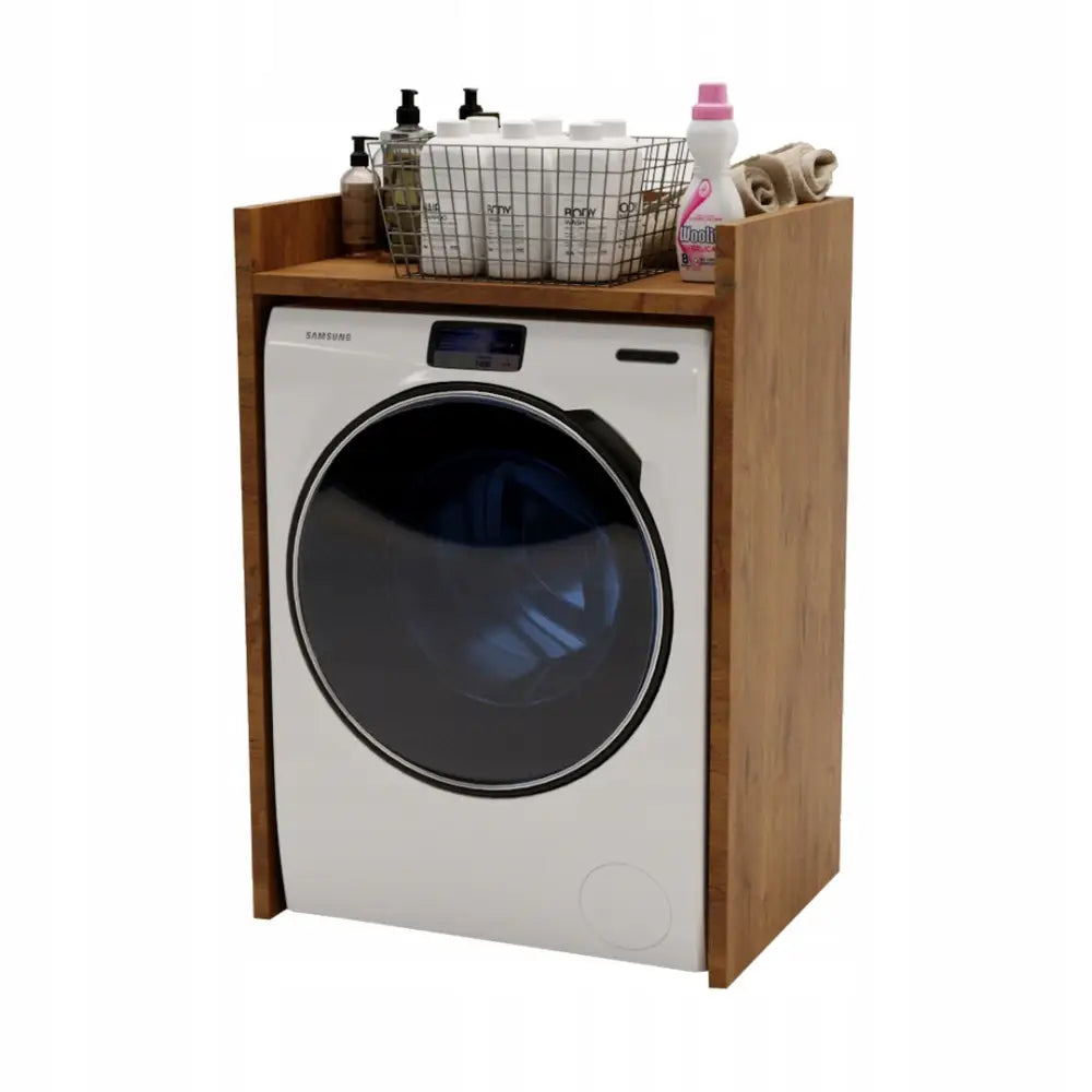 Skap for vaskemaskin Lancelot, frontvisning med vaskemaskin, vaskemidler, flasker og håndklær på toppen.
