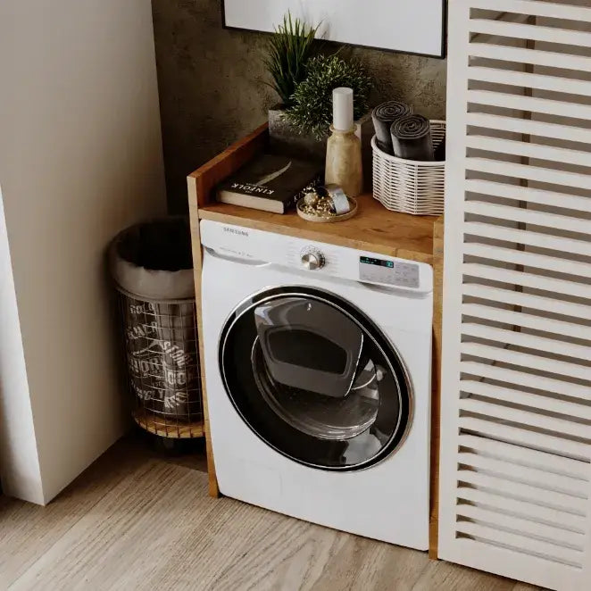 Skap for vaskemaskin Lancelot, frontvisning med hvit maskin, treomramming og dekor på skapets topp.