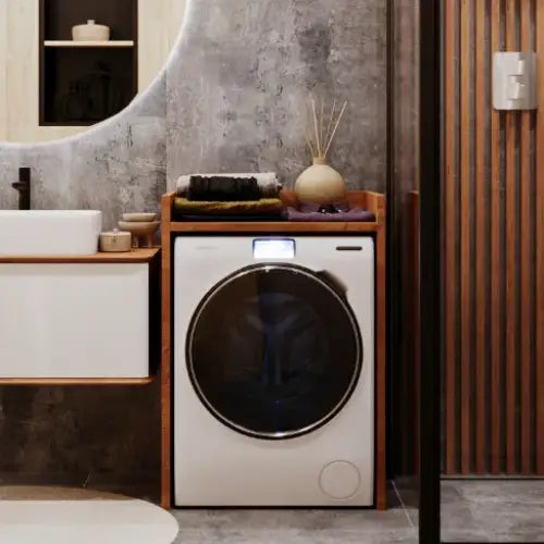 Skap for vaskemaskin Lancelot, hvit maskin med sort dør under treinnramming, håndklær og vase på toppen.