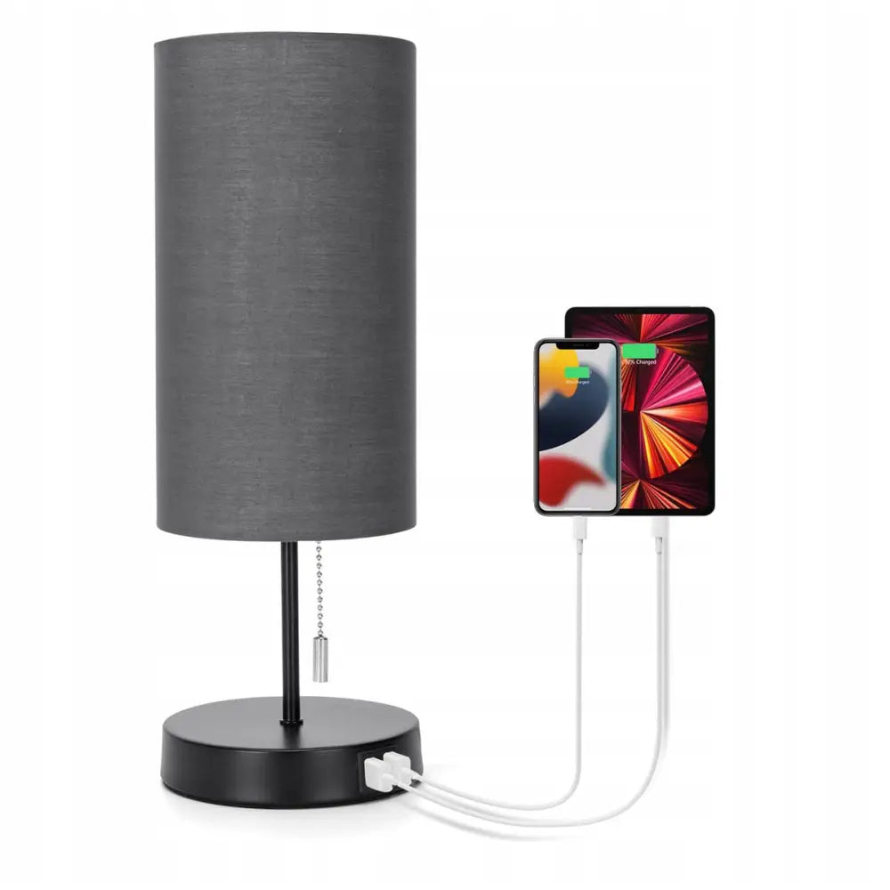 Skrivebordslampe med svart tekstilskjerm, to USB-porter i foten og to enheter til lading.