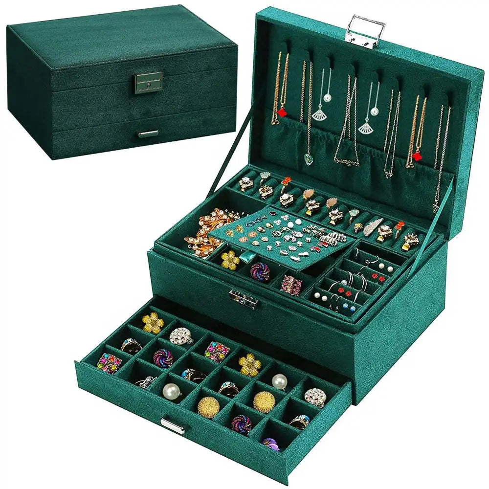Smaragdgrønt smykkeskrin i åpen posisjon, viser rominndeling, kroker og smykker i grønn fløyel.