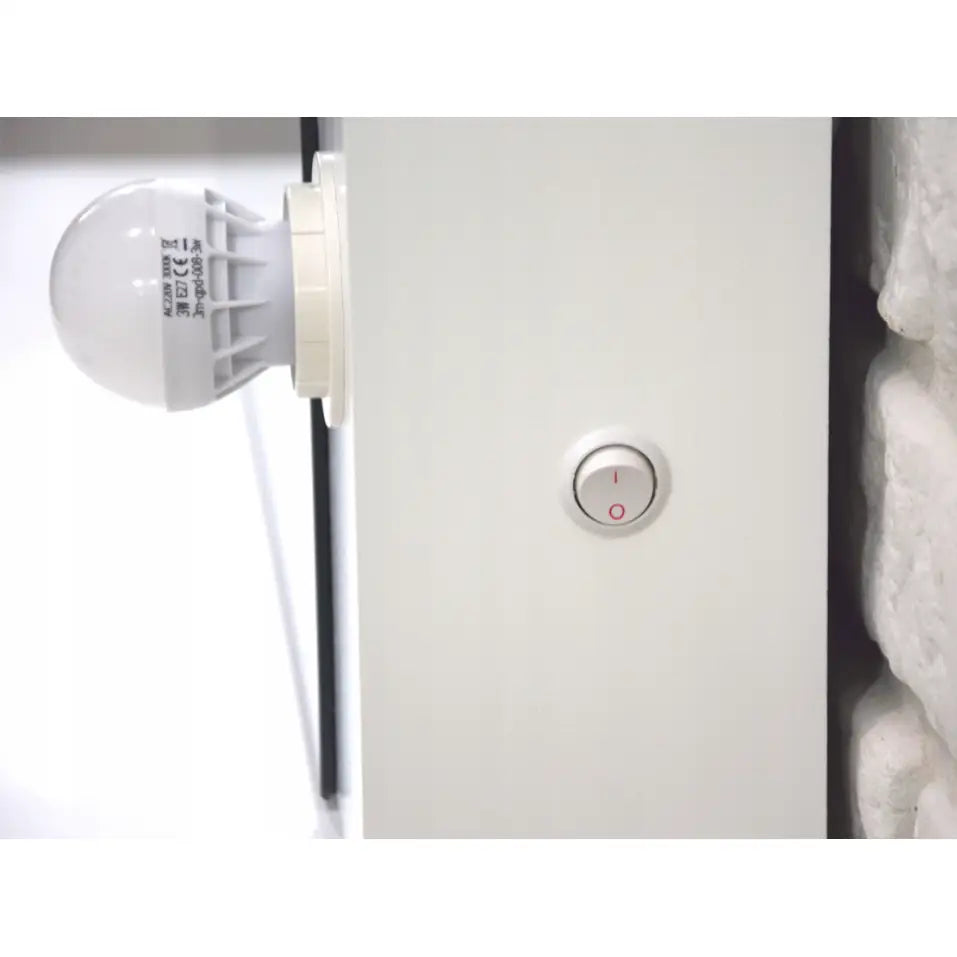 Sminkebord Broadway, detalj av hvit LED-pære og lysbryter montert i hvit ramme mot steinvegg.