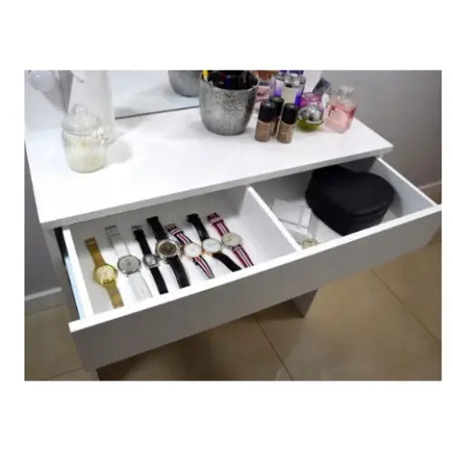 Sminkebord Broadway med speil og LED, åpen skuff med armbåndsur, sminke og sort eske på hvit bordplate.