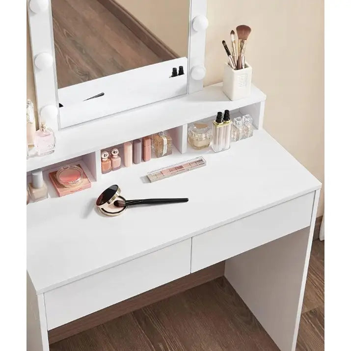 Sminkebord i hvitt sett ovenfra, LED-speil tent, sminkekoster i holder og ulike sminkeprodukter på bordet.