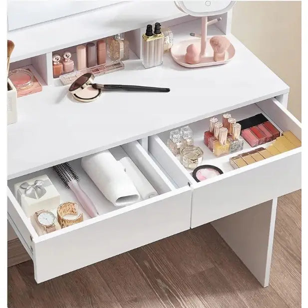 Sminkebord i hvit finish sett ovenfra, med to åpne skuffer fulle av sminke, smykker og skjønnhetsprodukter.