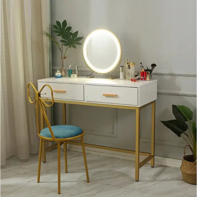Sminkebord i loft-stil med hvit plate, gullben, LED-speil og blå stol, sett fra skrå vinkel.