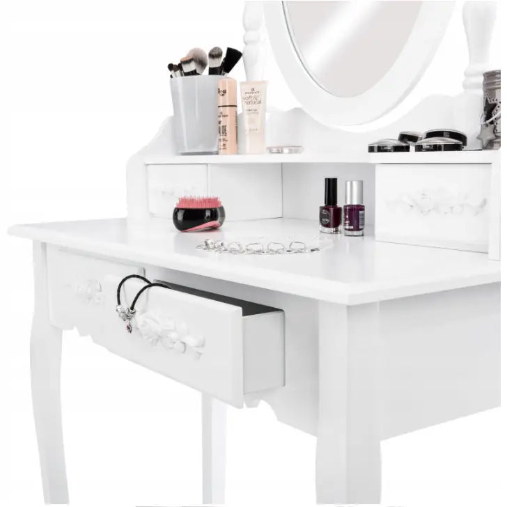 Sminkebord med speil i hvitt, skrå visning med åpne skuffer, sminke og smykker på utskåret bordplate.