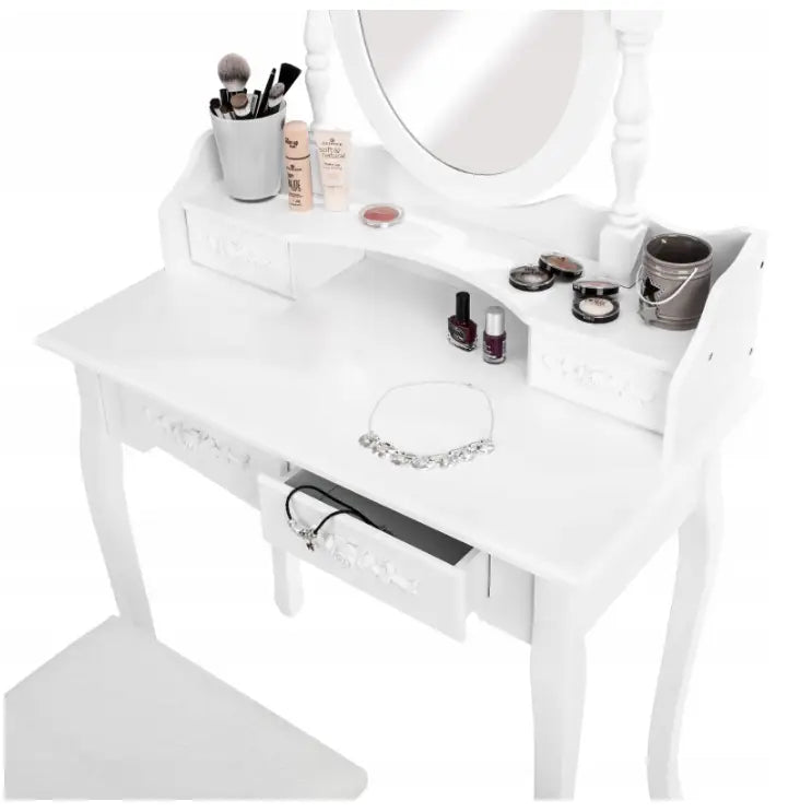 Sminkebord med speil i hvitt, sett skrått ovenfra med sminke, smykke og børster på bordplaten.