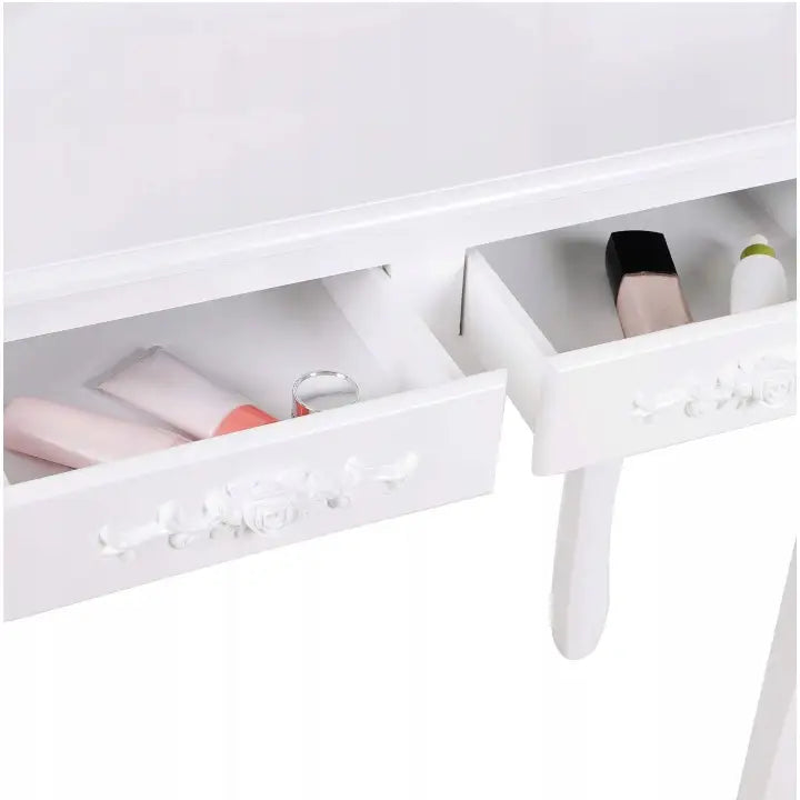 Sminkebord med speil og krakk, nærbilde av åpne hvite skuffer fylt med skjønnhetsprodukter, sett ovenfra.