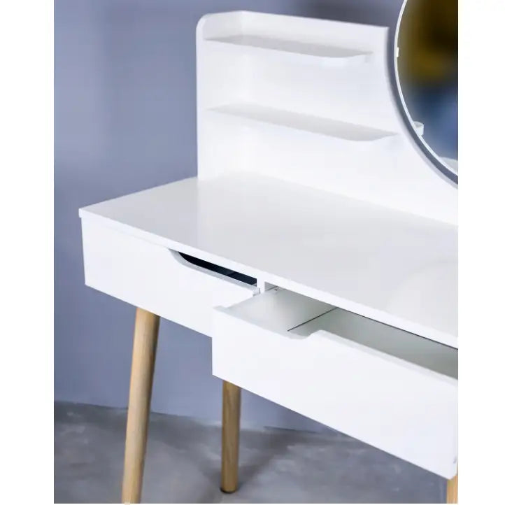 Sminkebord med speil i skandinavisk stil, hvite skuffer og hyller, runde treben, sett skrått.