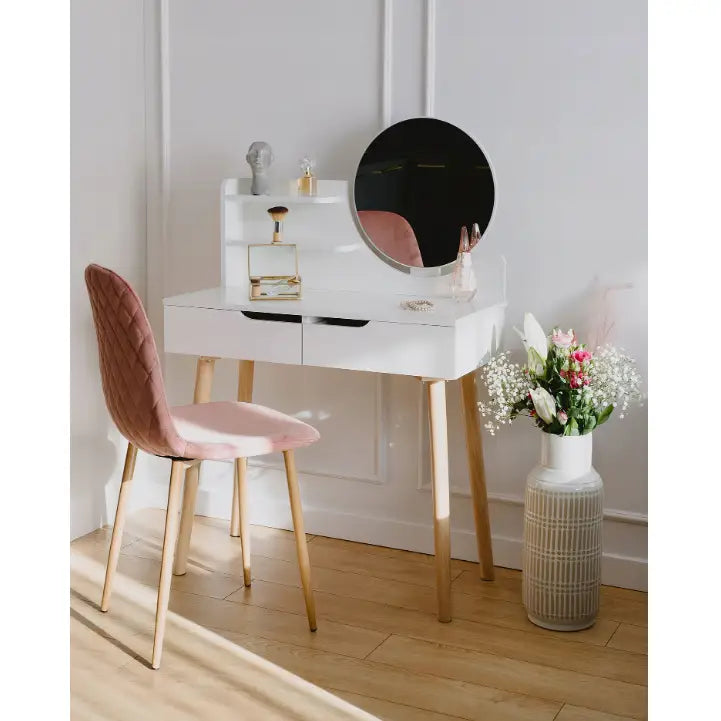 Sminkebord med speil, hvit bordplate, lyse treben, rosa stol og blomster i hvit vase ved siden av.