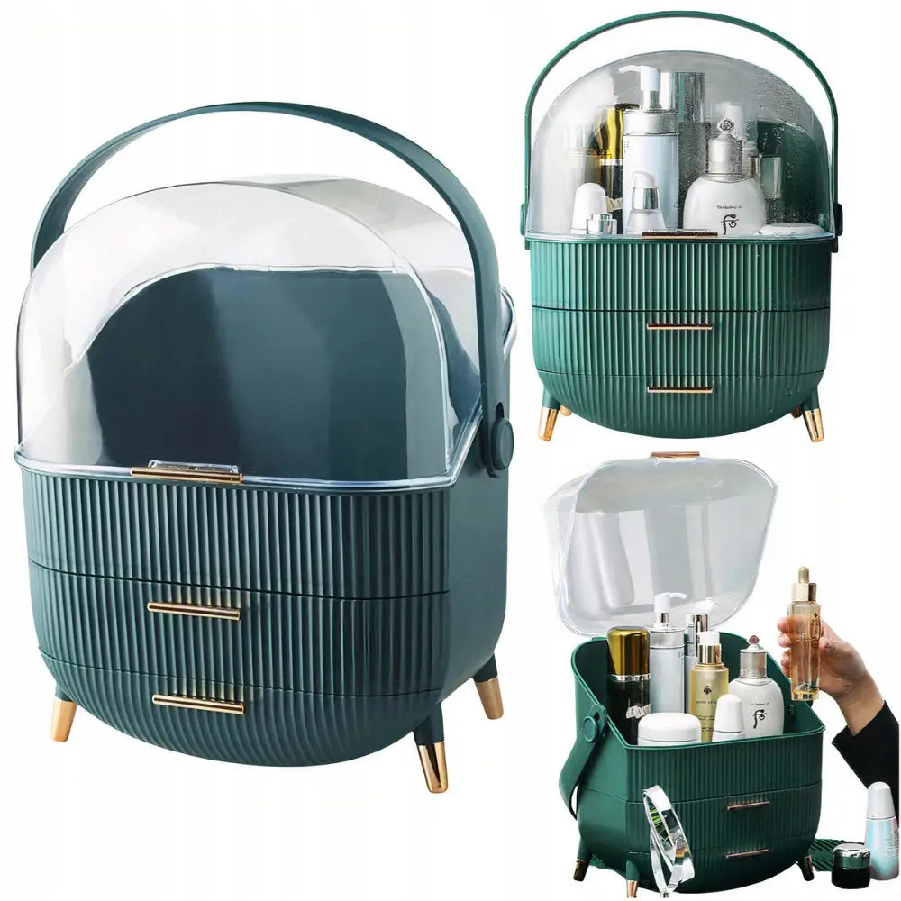 Smykkeskrin organizer i grønn plast med gullhåndtak, to skuffer og gjennomsiktig lokk, fylt med sminke.