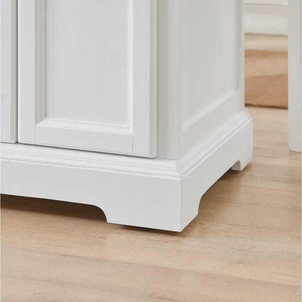 SoBuy kjøkkenøy, detalj av hvitmalt hjørne med profilert sokkel og hjul mot lyst tregulv.