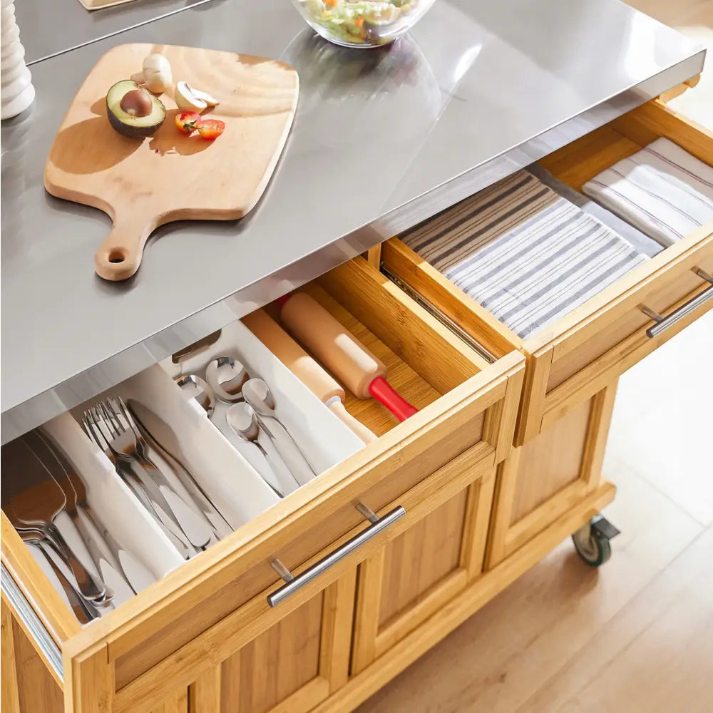Sobuy kjøkkenøy med ståloverflate, åpne skuffer viser bestikk, kjevler og kjøkkenhåndklær ovenfra.