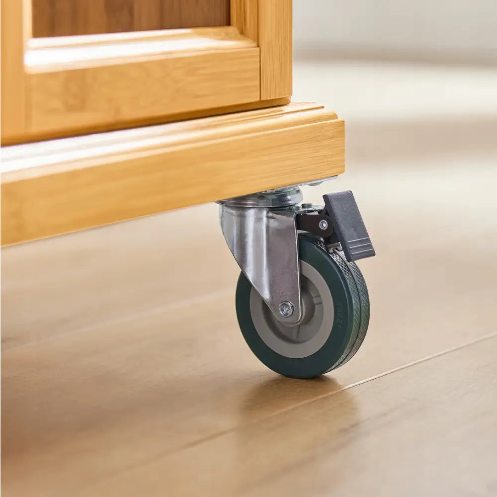 Sobuy kjøkkenøy, detaljvisning av mørkegrått hjul med brems montert på lyst treverk mot lyst tregulv.