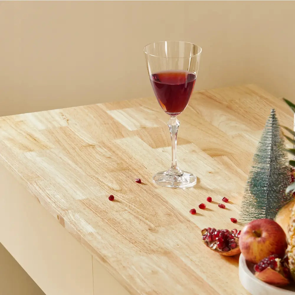 Sobuy kjøkkenøy, nærbilde av lys treplate dekorert med vinglass, granateple, eple og små grener.