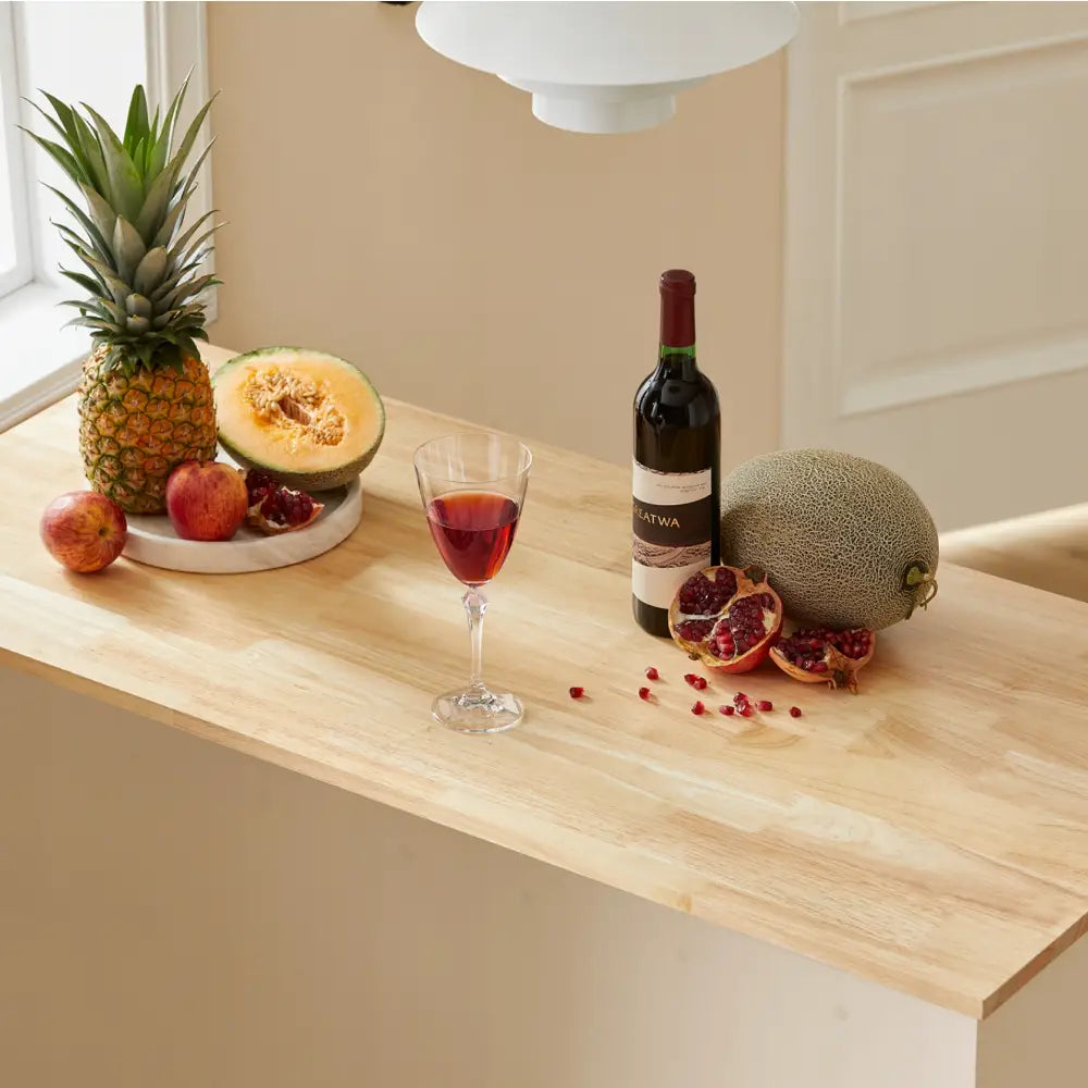 Sobuy kjøkkenøy med lys trebenk, fruktfat, glass rødvin og vinflaske sett fra siden i dagslys.