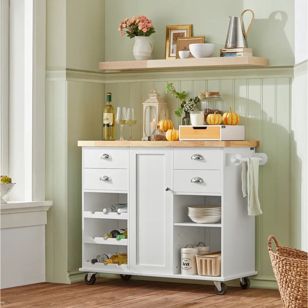 Sobuy kjøkkenøy i hvitt med lys treplate, fire skuffer, åpne hyller fylt med flasker og servise, sett forfra.